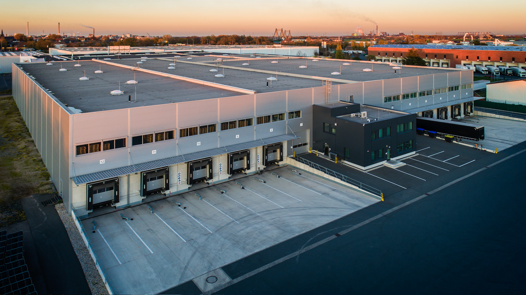 Logistikzentrum mit Verladehof und Andocktoren aus der Luft im Abendlicht